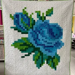 A beautiful pixelated rose quilt in shades of blue and green. This modern technique uses small squares of fabric to create a large, stunning image, perfect for a statement wall hanging.