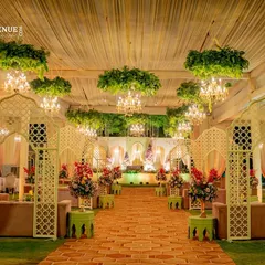 Imagine walking through an enchanted garden. I designed this elegant reception walkway with jaali arches, lush greenery suspended from the ceiling, and dozens of sparkling chandeliers. This design creates a truly magical pathway for you and your guests.
