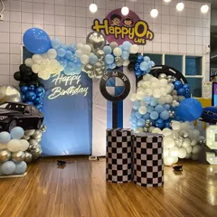 A high-energy BMW car theme decoration for a young racing fan's 5th birthday, complete with a blue and silver balloon arch, checkered flag details, and a large car cutout.