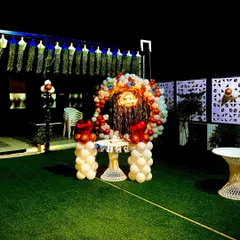 A beautiful birthday setup on an open terrace. This features a circular balloon arch with a shiny backdrop and a neon sign, perfect for cake cutting and photos.