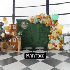A modern and rustic baby shower setup featuring a green foliage wall, a neon "Oh Baby" sign, and large wooden "BABY" blocks. This elegant design is perfect for a chic celebration.