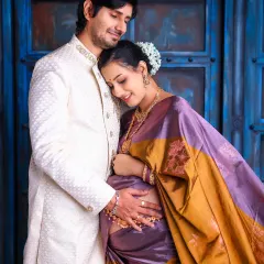 The bond between partners shines through in this elegant traditional maternity portrait. Dressed in a beautiful silk saree, the couple shares a quiet, loving moment, showcasing a timeless connection.