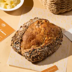 A rustic, seeded loaf of sourdough bread. The styling is simple and natural, letting the quality of the bread speak for itself.