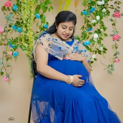 A serene portrait of a mother-to-be in a beautiful royal blue gown. The delicate floral backdrop in our studio adds a touch of elegance and softness to the image.