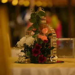 A close-up of a romantic table centerpiece featuring a vintage-style birdcage filled with fresh flowers, set on a mirrored base to reflect the soft, ambient light.