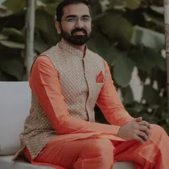 This is a great option for a Mehendi or Haldi function. The outfit consists of a bright orange silk kurta paired with a custom-embroidered bandi jacket, creating a look that is both festive and comfortable.