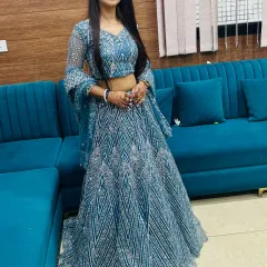 A client looking elegant in a teal lehenga with geometric silver sequin work. The bell sleeves on the choli add a modern touch.