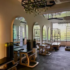 I designed our second studio space with arched mirrors and hanging greenery to feel open and inspiring. It's equipped with reformer machines and Pilates chairs for a varied and complete workout.