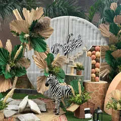 This boho jungle setup features a zebra prop, a balloon-filled marquee number '1', and a rustic slatted backdrop for a stylish first birthday.
