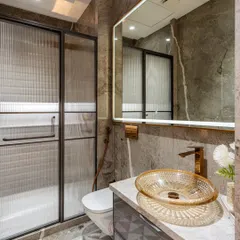 A close-up of the vanity, showcasing the beautiful textured glass basin and the brushed gold faucet. The combination of materials and finishes adds a layer of luxury to this grey marble bathroom.