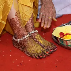 A beautiful shot of bridal feet during a haldi ceremony. The rich henna stain stands out beautifully, adorned with traditional silver anklets.