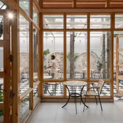 A small, intimate seating area looks out into the main courtyard. The use of extensive glazing dissolves the boundary between the indoor and outdoor dining spaces.
