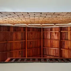 A view from the stairwell of the Vinaya residence, showing the layers of the ceiling. You can see the reclaimed wood paneling and the tiled roof structure, an honest expression of how the house is built.