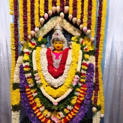 A deity at Vasavi Matha Temple adorned with elaborate, multi-layered garlands of fresh flowers and lotus buds.