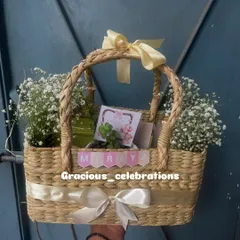 This beautiful cane basket was part of a 250-piece order for a first birthday. It's filled with a cake loaf, organic honey, cookies, a jade planter, and a scented candle, all decorated with fresh flowers.