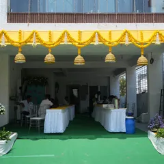 A closer look at the entrance decor for a housewarming. The bright yellow structure adorned with marigold garlands and traditional bells creates a festive and auspicious welcome.