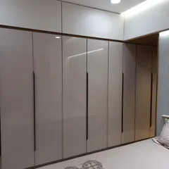 A floor-to-ceiling hinged wardrobe in a high-gloss beige finish with long, elegant black handles. This design maximizes storage by extending all the way to the ceiling, providing ample space for all clothing and accessories.