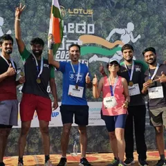 A group of triumphant runners posing with their medals and the flag after completing the Freedom Run. The sense of accomplishment is a shared experience.
