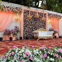 We designed this classic and romantic reception stage, featuring a dense wall of pink and white roses. The elegant drapes, vintage-style sofa, and sparkling chandeliers added a touch of royal grandeur to the evening.