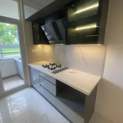 A view of the cooking area in a modern kitchen, featuring a chimney hood integrated into the overhead cabinets and a durable countertop, ensuring the space is practical for daily use.
