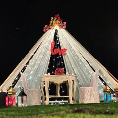 A beautiful view of the romantic tent proposal setup, illuminated by fairy lights against the night sky.