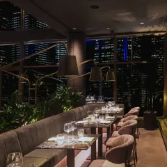 The interior of One40 Rooftop, where plush seating and custom lighting create an intimate atmosphere against the vast city view. This space was featured in Forbes for its elevated design.