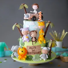 An amazing three-tiered jungle safari cake for a first birthday. This detailed creation features a whole crew of adorable fondant animals, including a lion, giraffe, monkey, and hippo.