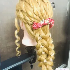 This side view of a bridal practice braid on a mannequin shows the detailed weaving and volume at the crown. Students learn to combine different braiding techniques for a unique finish.