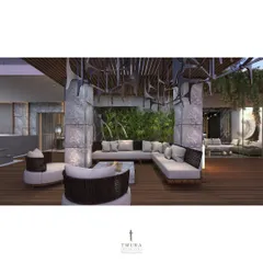 An outdoor seating area designed for comfort and style. The space is defined by stone-clad pillars and a unique, sculptural ceiling installation, with a backdrop of lush vertical greenery.