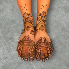 A majestic peacock-themed design for bridal feet. The peacocks' feathers flow beautifully down the feet, complemented by jhumka and floral details on the ankles.
