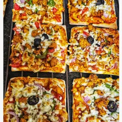 A close-up of the tandoori chicken pizza squares included in our birthday snack boxes. A cheesy and flavorful treat.