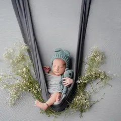 Gently cradled and surrounded by delicate baby's breath. This hanging prop pose is one of our favorites for creating an artistic and ethereal newborn photograph, highlighting how small and precious they are.