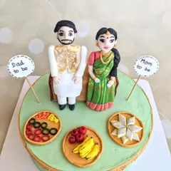 A traditional baby shower cake with incredible detail. I handcrafted the fondant couple in ethnic wear, along with miniature plates of sweets, fruits, and bangles to celebrate the occasion.