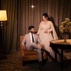 A sophisticated and elegant portrait of the couple in their hotel suite. The warm, ambient lighting creates a cozy and intimate atmosphere for this reception look.
