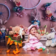 Another angle from the bunny-themed session, this time with the baby sitting beside the cart. Her happy expression shows how much she enjoyed the playful environment.