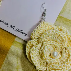 A close-up of my cream-colored rose earring, handcrafted from cotton thread. I've added a small pearl in the center for an elegant touch.