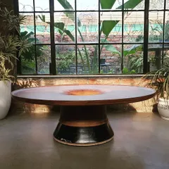 This sculptural dining table features a solid wood top with a unique concave center, resting on a handcrafted ceramic and wood base. It is a perfect example of how we blend different materials to create a functional work of art.
