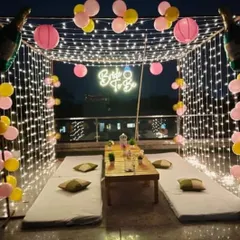 For a trendy and modern celebration, I can arrange a rooftop cabana like this one for a 'Bride to Be' party. The setup includes a canopy of fairy lights, comfortable low seating, a custom neon sign, and balloons to create a magical atmosphere.