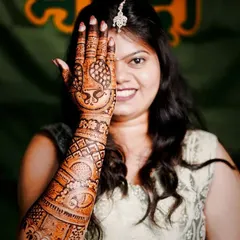 A classic bridal pose, with the intricate mehendi on one hand framing the bride's happy smile.