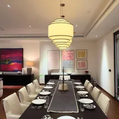 This large, 12-seater dining table was custom-built with a dark wood finish to anchor a spacious dining room. Its clean, simple lines allow the surrounding art and decor to stand out, creating a perfect setting for gatherings.