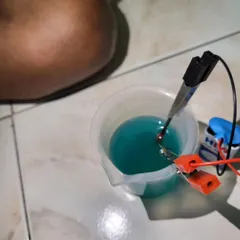 A close-up of a simple battery and electrode setup in a beaker, the core of many of our fun chemistry experiments.