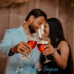 A soft-focus shot of a couple sharing a toast, capturing a celebratory and intimate moment. The "Love Story in Progress" text adds a sweet narrative touch.