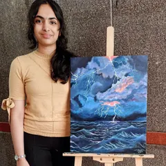 Shreya proudly displays her dramatic seascape painting of a lightning storm. In this piece, she learned to capture the energy of the storm by blending dark clouds and creating the bright, sharp lines of lightning over the turbulent sea.