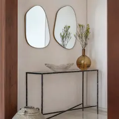 A detail shot from Apartment 1600, featuring a forged iron console table and organic-shaped mirrors. This composition of textures and forms creates an elegant and artful moment in the entryway.