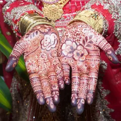 A detailed shot of a bride's hands, showcasing the rich, dark color and intricate patterns of her bridal mehndi.