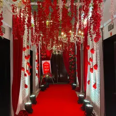 A truly dramatic and romantic entranceway. We lined the hall with red carpets and drapes, and created a ceiling of hanging red floral strings interspersed with elegant chandeliers.