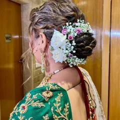 A beautiful and full bridal bun, intricately woven and adorned with fresh white roses and baby's breath. This is a timeless choice for any wedding ceremony.
