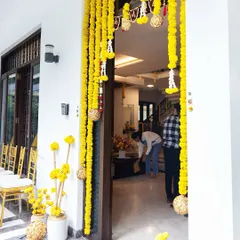 A beautiful doorway framed with hanging marigold garlands. Inside, our team is seen making the final touches, ensuring every detail is perfect for the ceremony.