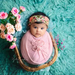 Wrapped in pink and surrounded by flowers. This newborn portrait combines a cozy swaddle with a beautiful floral theme for a delicate and artistic image.