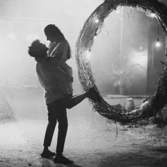 A dramatic black and white silhouette of a couple against a prop, creating a moody and artistic pre-wedding photo. The high contrast and composition give it a timeless, cinematic feel.